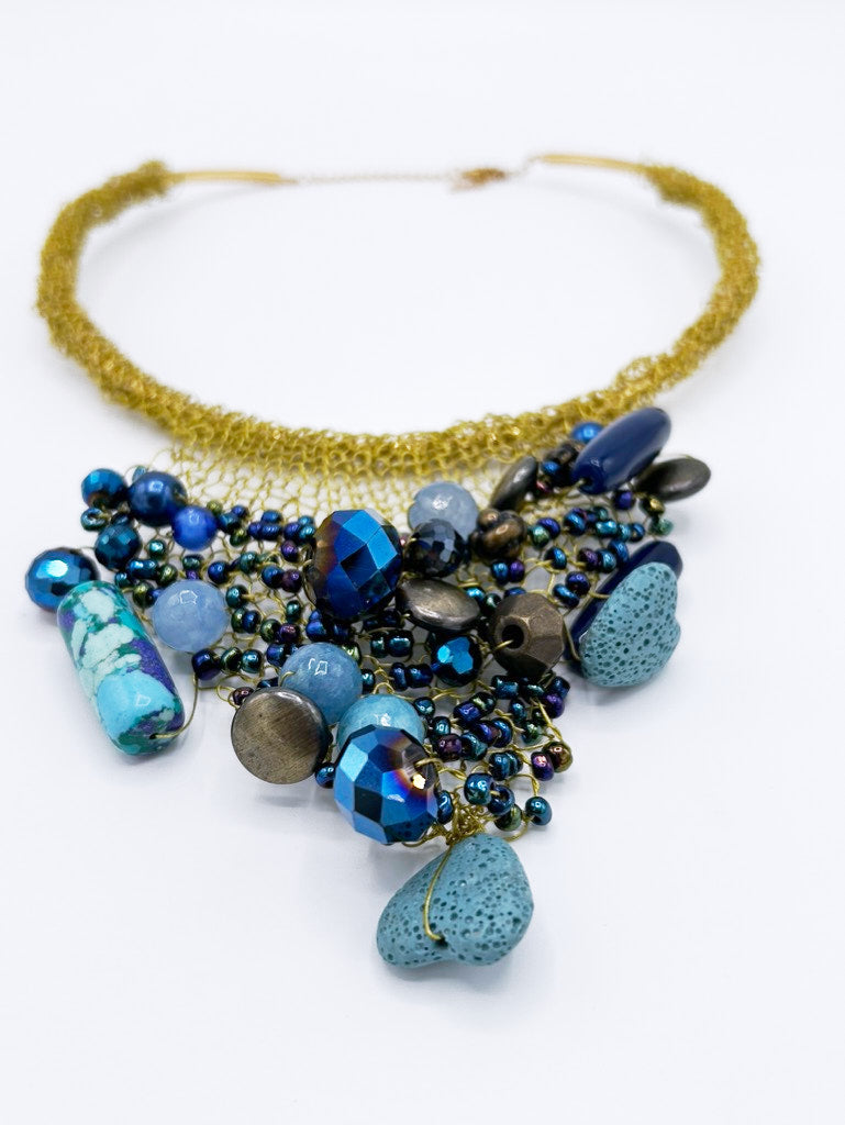 Collar tejido en dorado con piedras en gama de azules