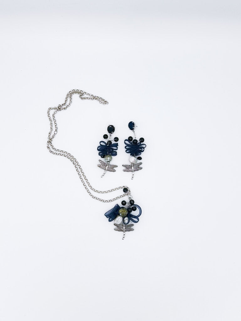 Collar en cadena plateada con libélula de acero y serpentina entrelazada con piedras negras, y pendientes a juego