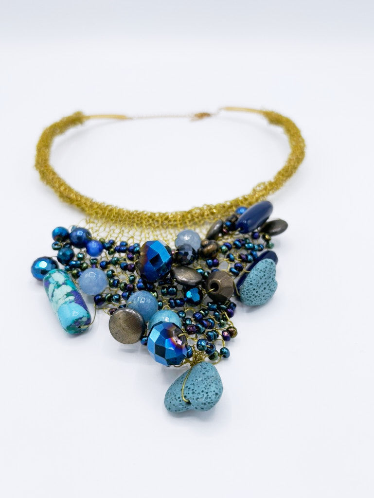 Collar tejido en dorado con piedras en gama de azules
